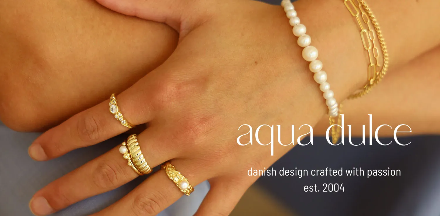 Aqua Dulce smykker – guldringe og perlearmbånd båret på hænder, dansk design siden 2004